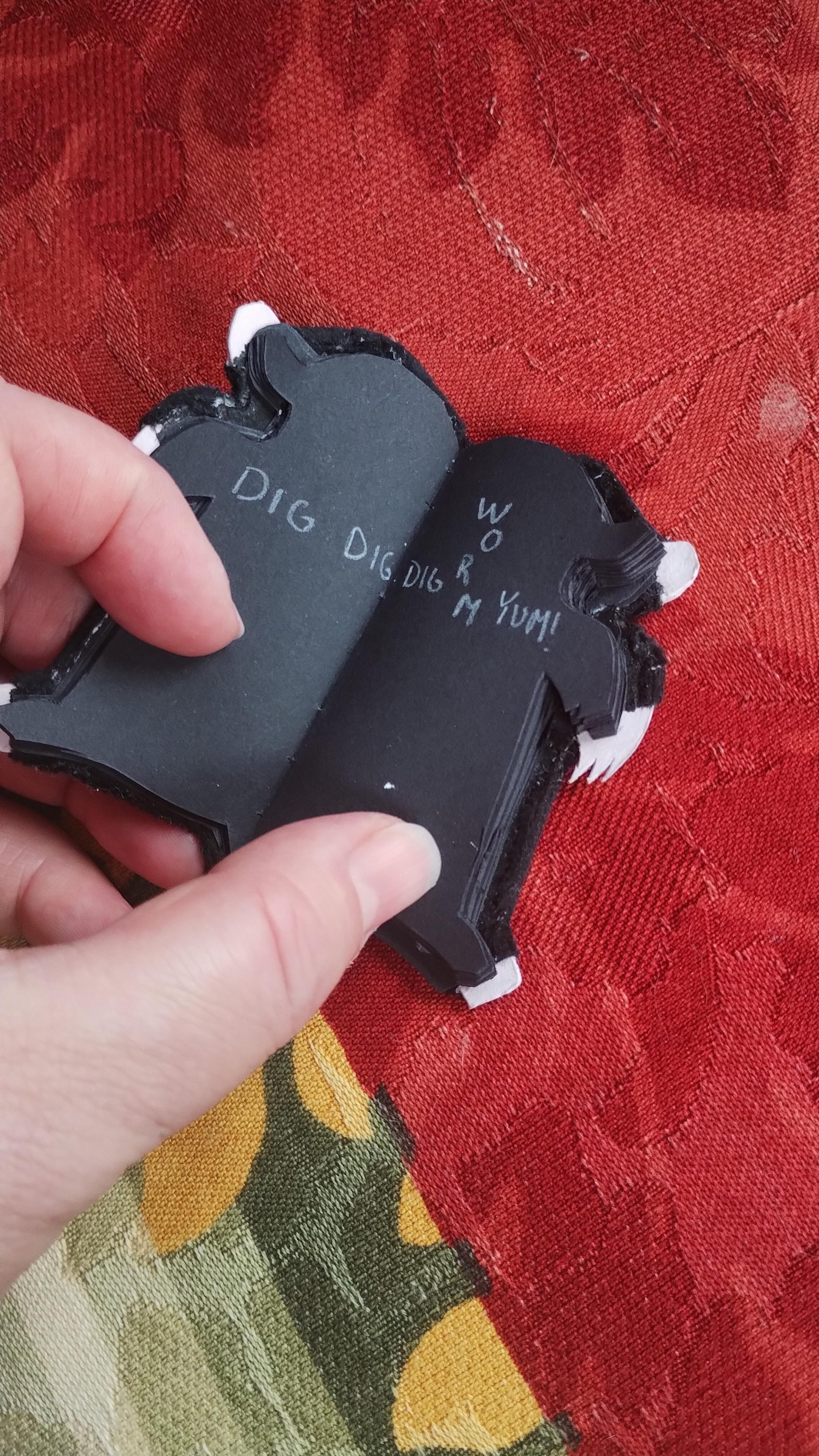 The mole book is opened to another page. There is text written in white pencil that goes across two pages that reads DIG DIG WORM DIG